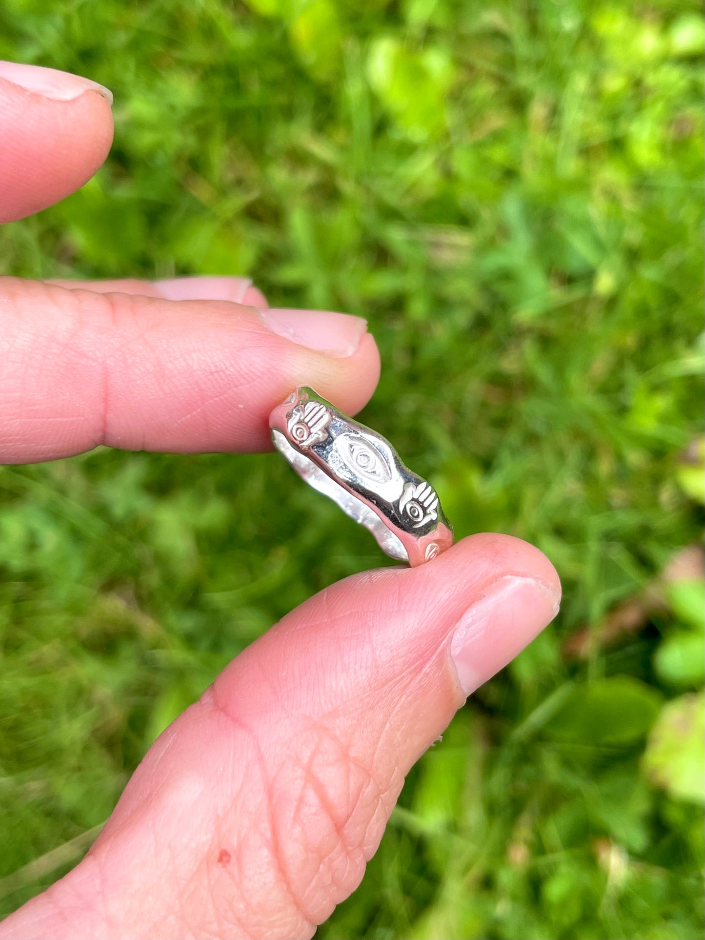 wide shot of eye and hamsa symbols hand-stamped on textured sterling silver ring