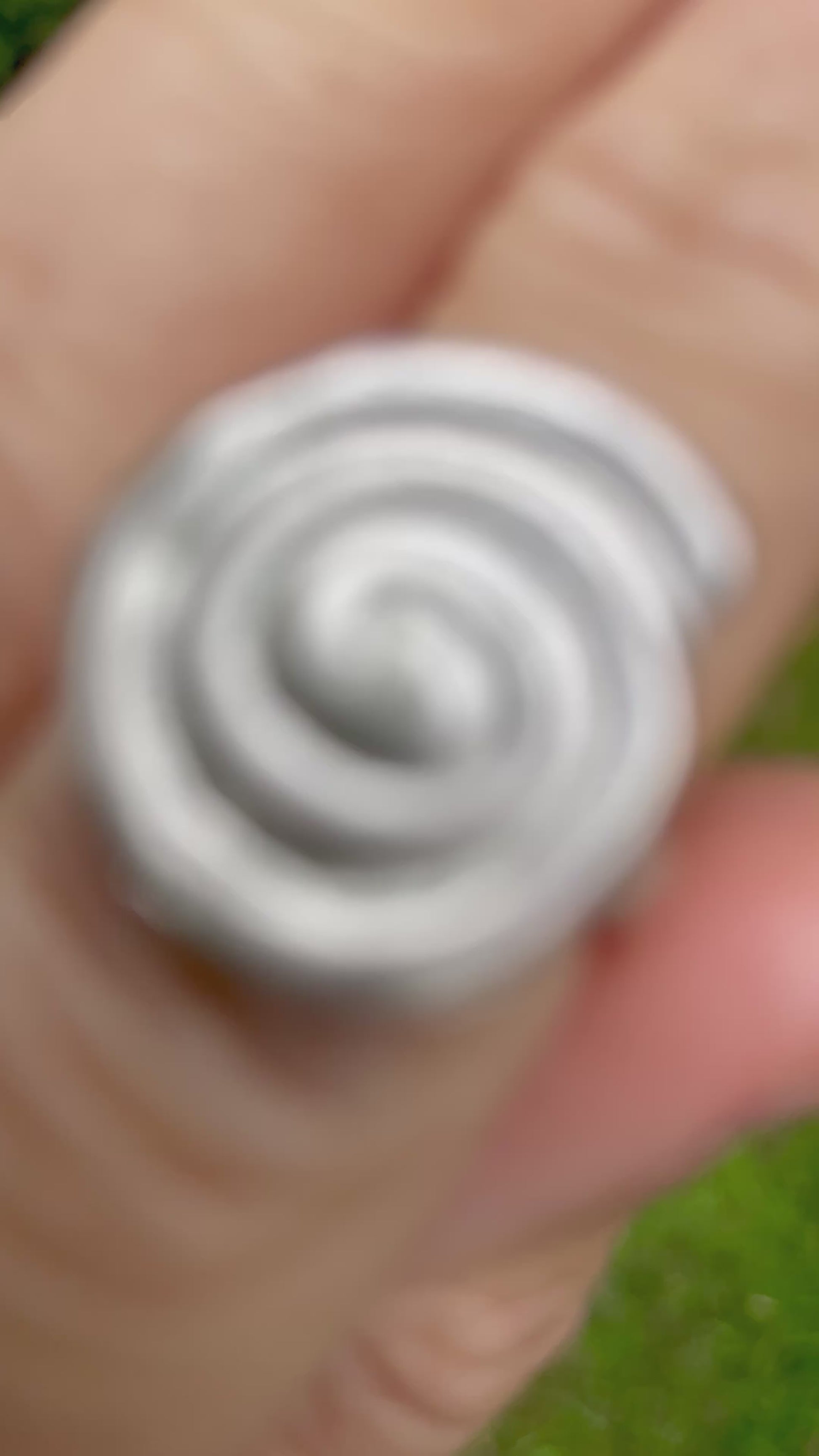 sterling silver sandcast spiral ring on hand with green forest background