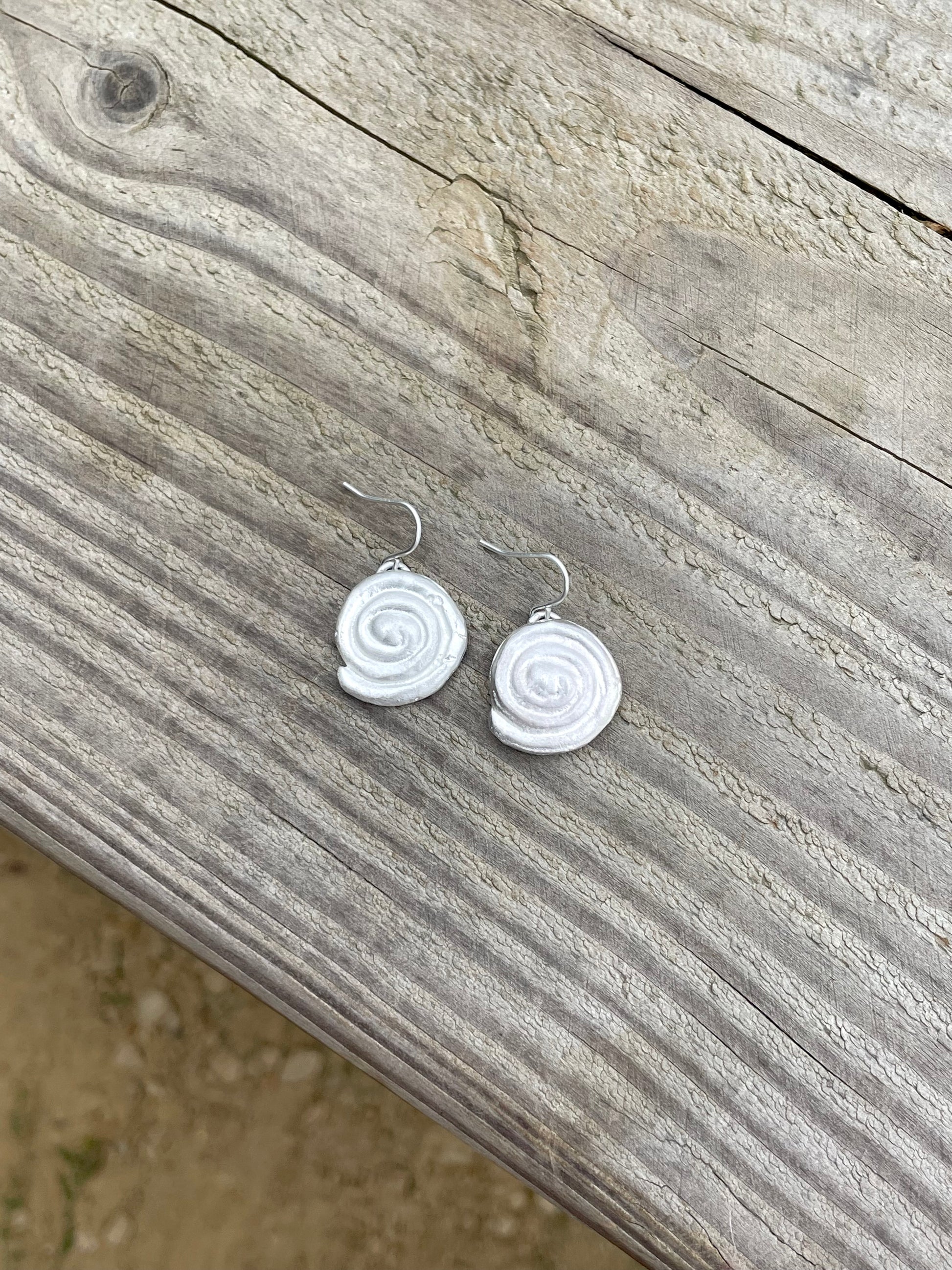 Silver spiral earrings on a wooden surface